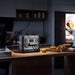Jackery Explorer 1500 Ultra Portable Power Station on a kitchen counter with a person opening a refrigerator in the background.