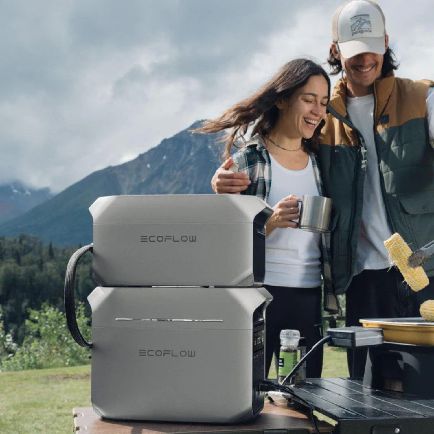 A couple grilling outdoors in a mountain setting with EcoFlow DELTA 3 Series Smart Extra Batteries in a portable station powering their equipment