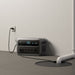 Anker SOLIX C2000 Gen 2 Portable Power Station plugged into a wall outlet on a neutral background