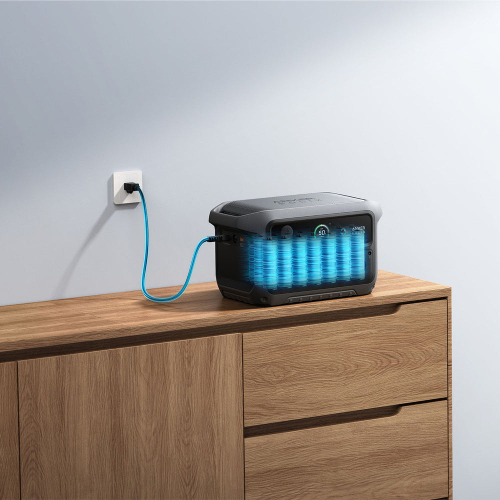 Anker SOLIX C2000 Gen 2 Portable Power Station with blue light on a wooden surface, plugged into an outlet.