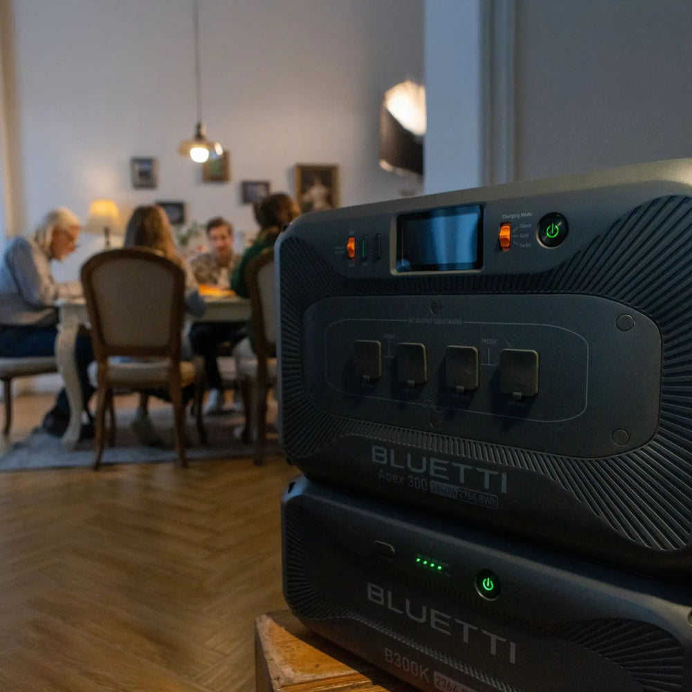 BLUETTI Apex 300 Portable Power Station with B300K2 Battery in a room with people sitting at a table.