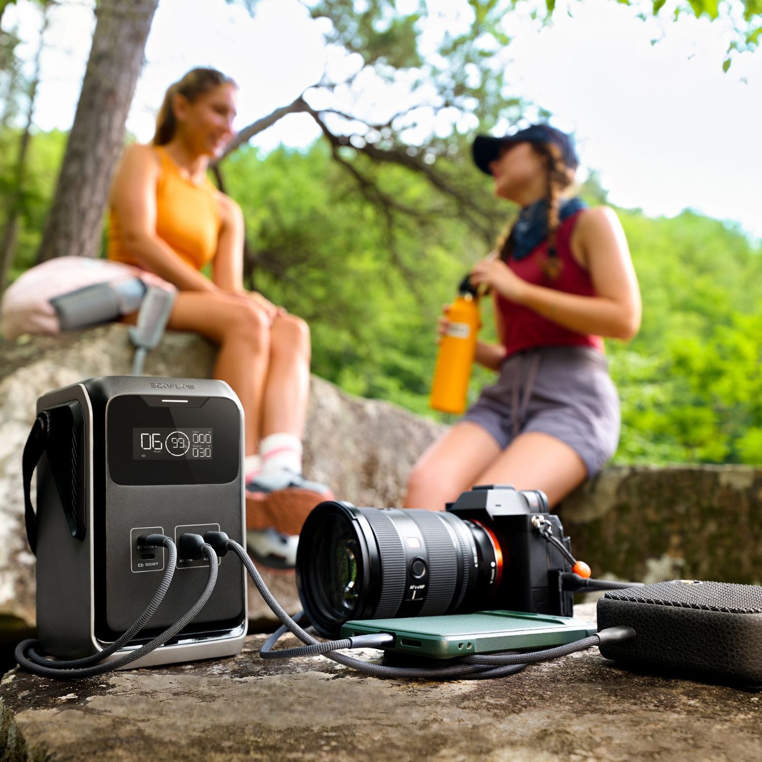 Camera and EcoFlow TRAIL 200DC Portable Power Station on a rock with two people in the background