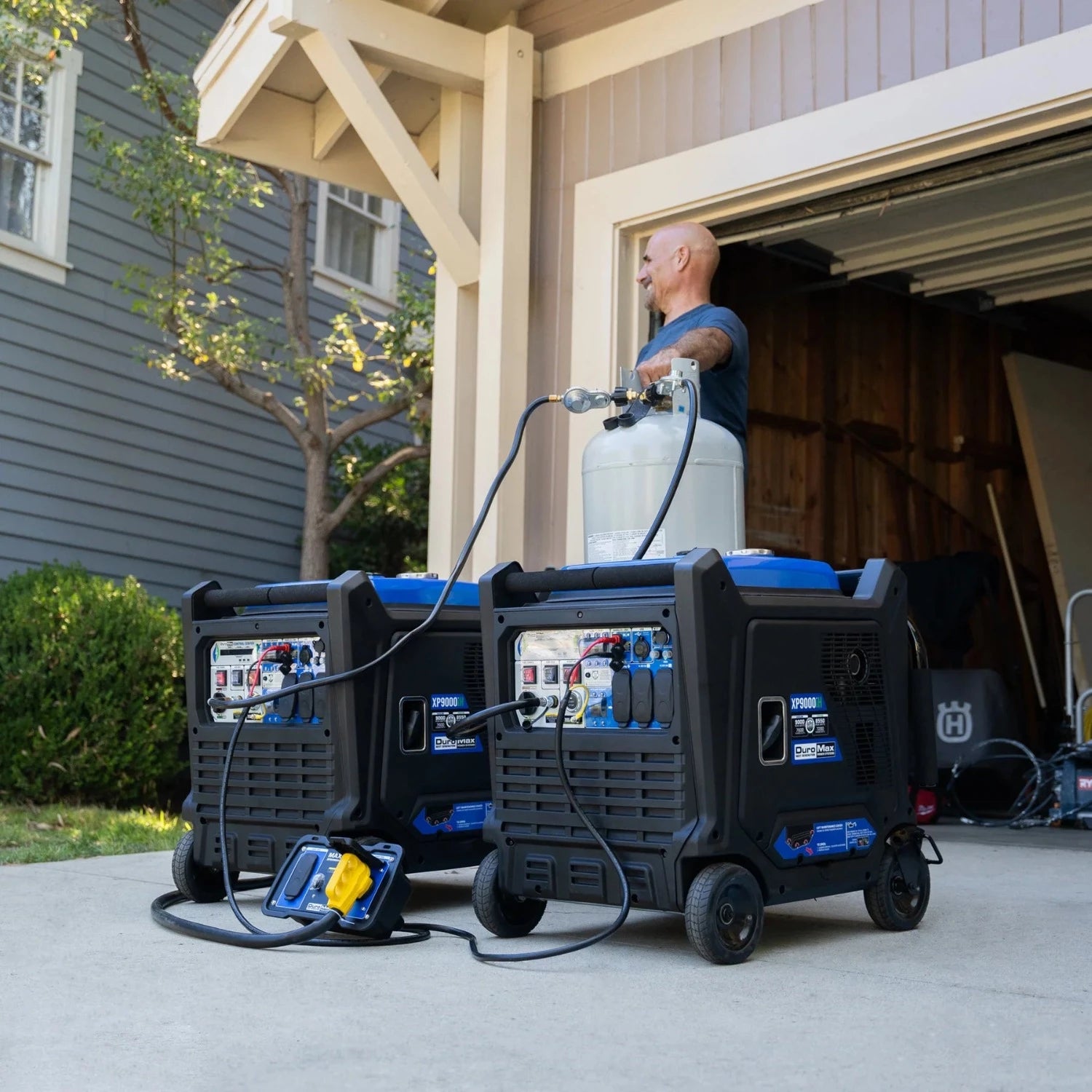 DuroMax Inverter Parallel Kit for XP9000iH Generator In Front Of A Garage Connecting Two Generators With A Man Standing Next To The Propane Tank