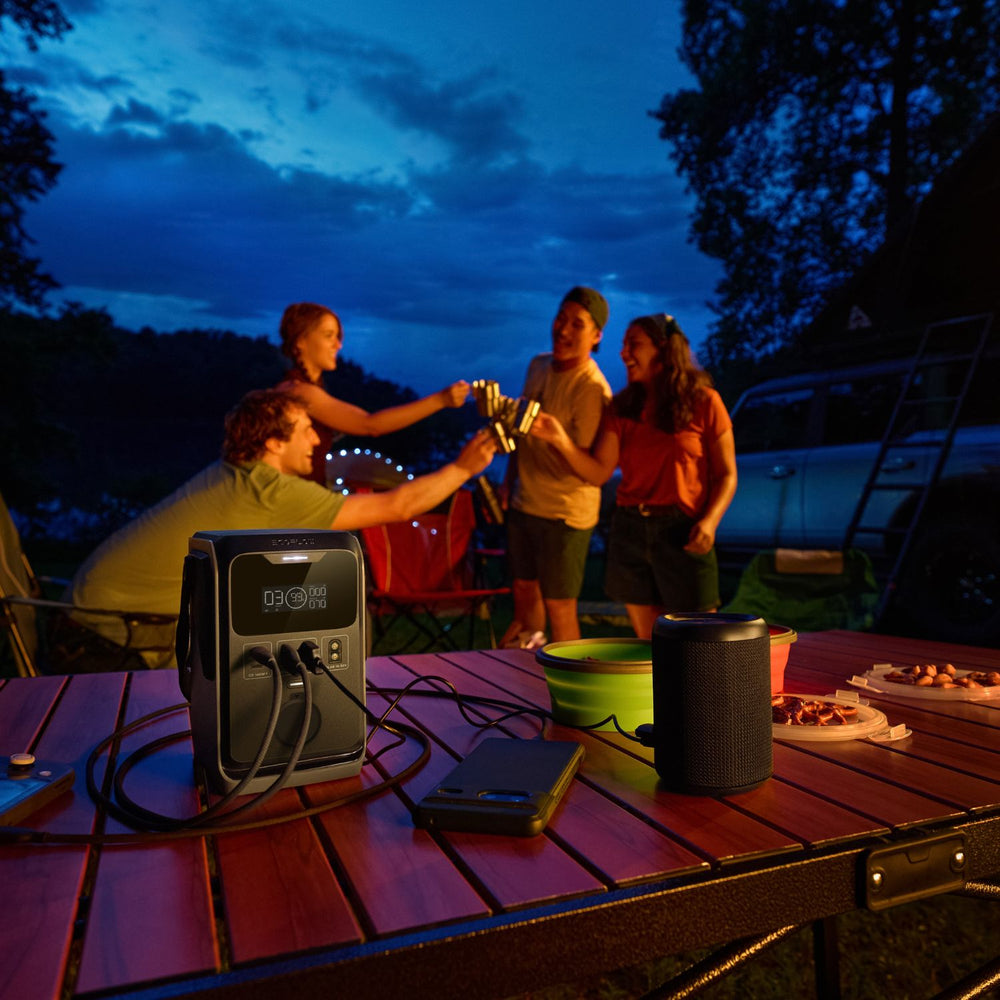 Group of people enjoying a campfire at night with a EcoFlow TRAIL 300DC Portable Power Station on a table.
