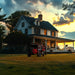 House with a red tractor in front during sunset and with DuroStar DS13000MXT Tri-Fuel Generator in front