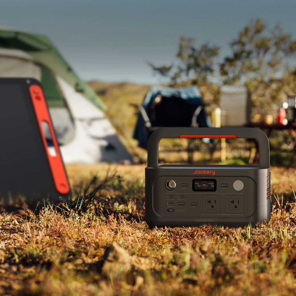 Jackery Explorer 600 v2 in a camping setting with tents in the background