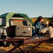 Jackery Explorer 600 v2 on a camping table with a tent and people in the background