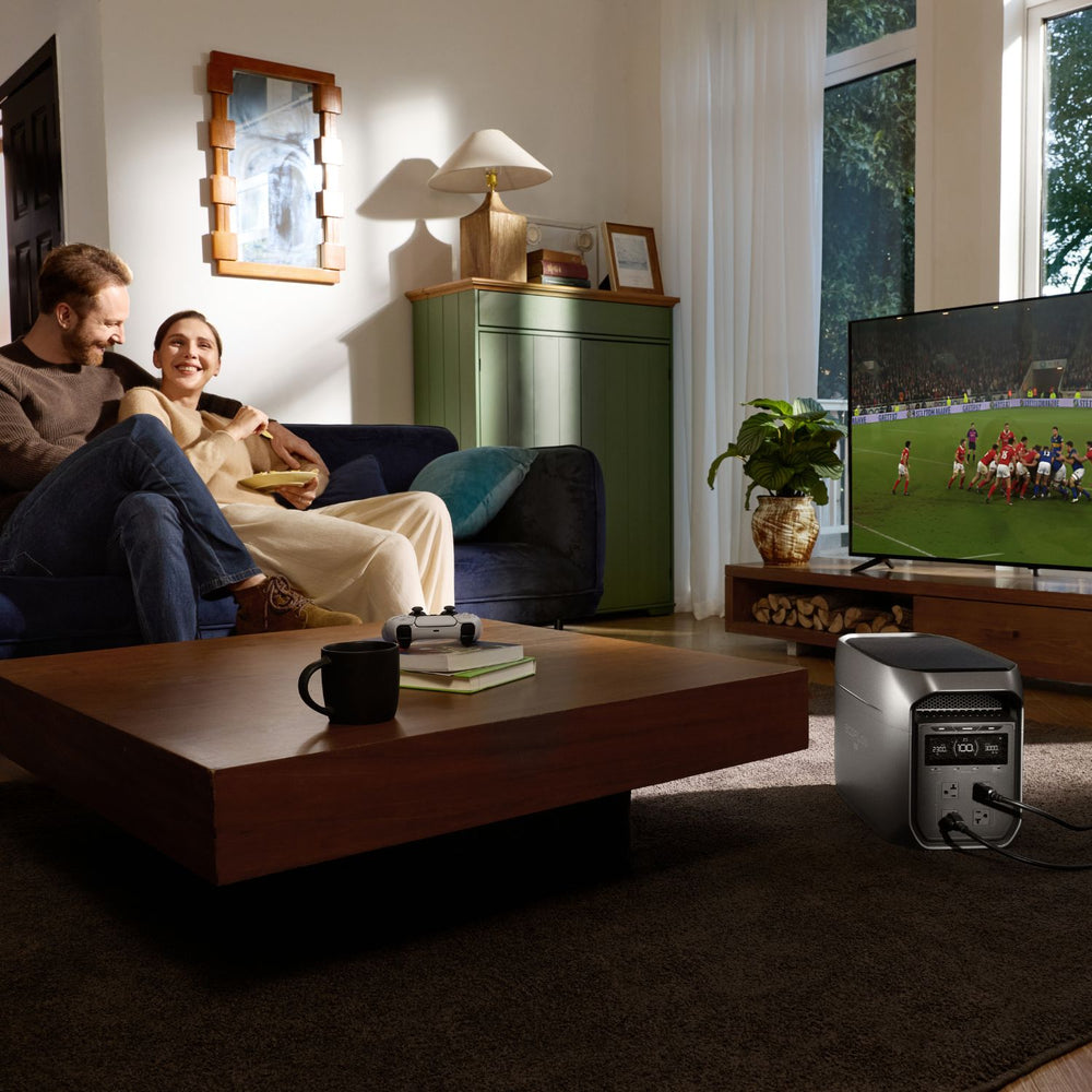 Living room with a couple watching TV, a coffee table with a cup, and a EcoFlow DELTA 3 Max Plus Portable Power Station on the floor.