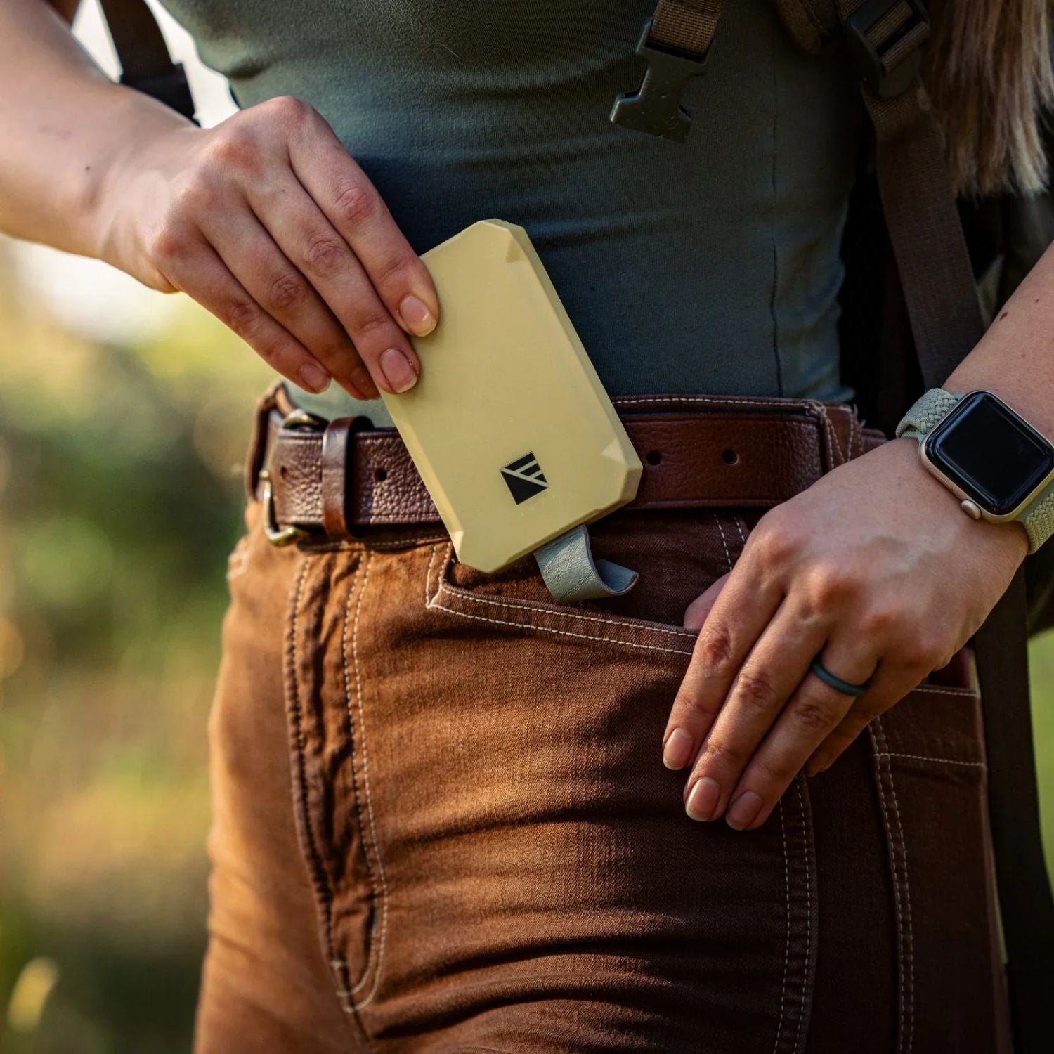 Man Putting the Dark Energy Poseidon Nano Power Bank - Desert Into His Pocket