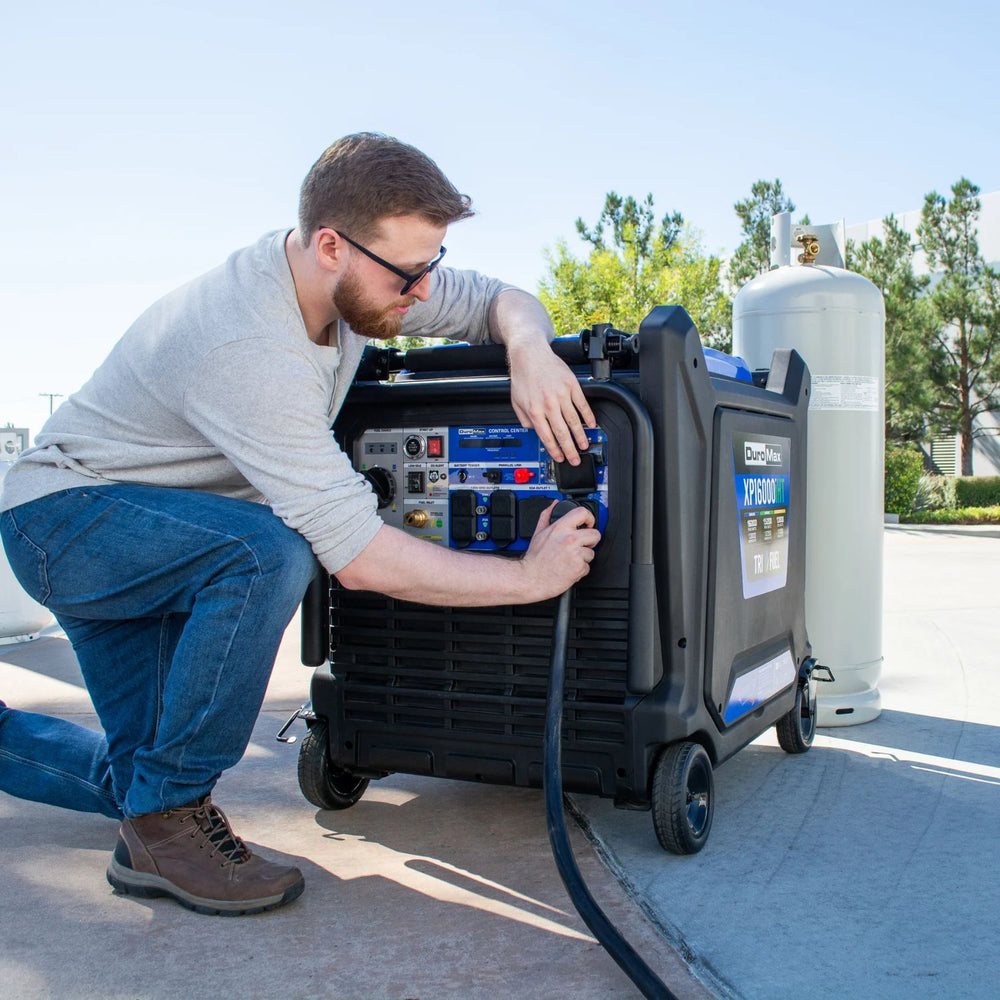 Man operating a DuroMax XP16000iHT Tri-Fuel Generator outdoors with trees and clear sky in the background