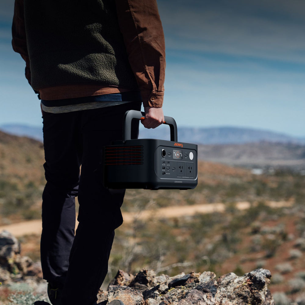 Person holding a Jackery Explorer 600 v2 in a mountainous landscape