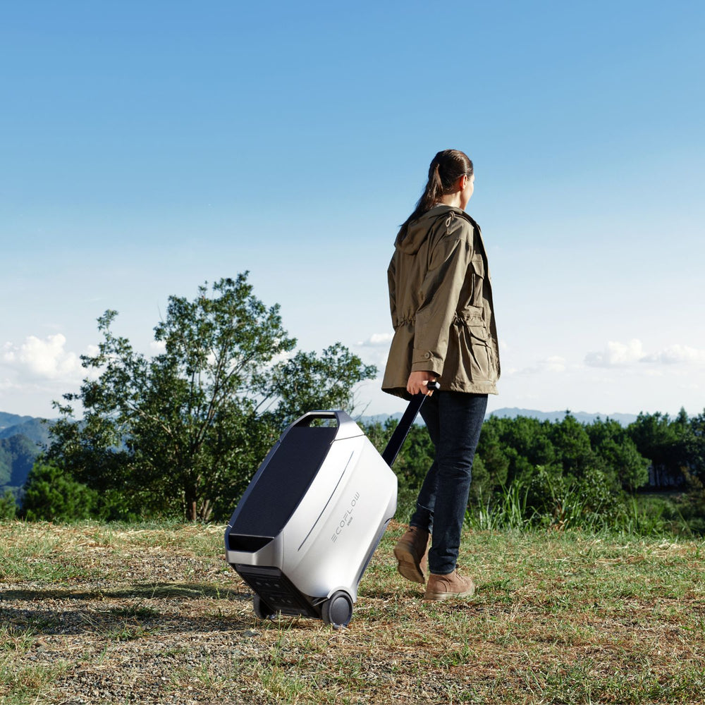 Person pulling a EcoFlow DELTA 3 Ultra Plus Portable Power Station through a scenic outdoor area with trees and blue sky.