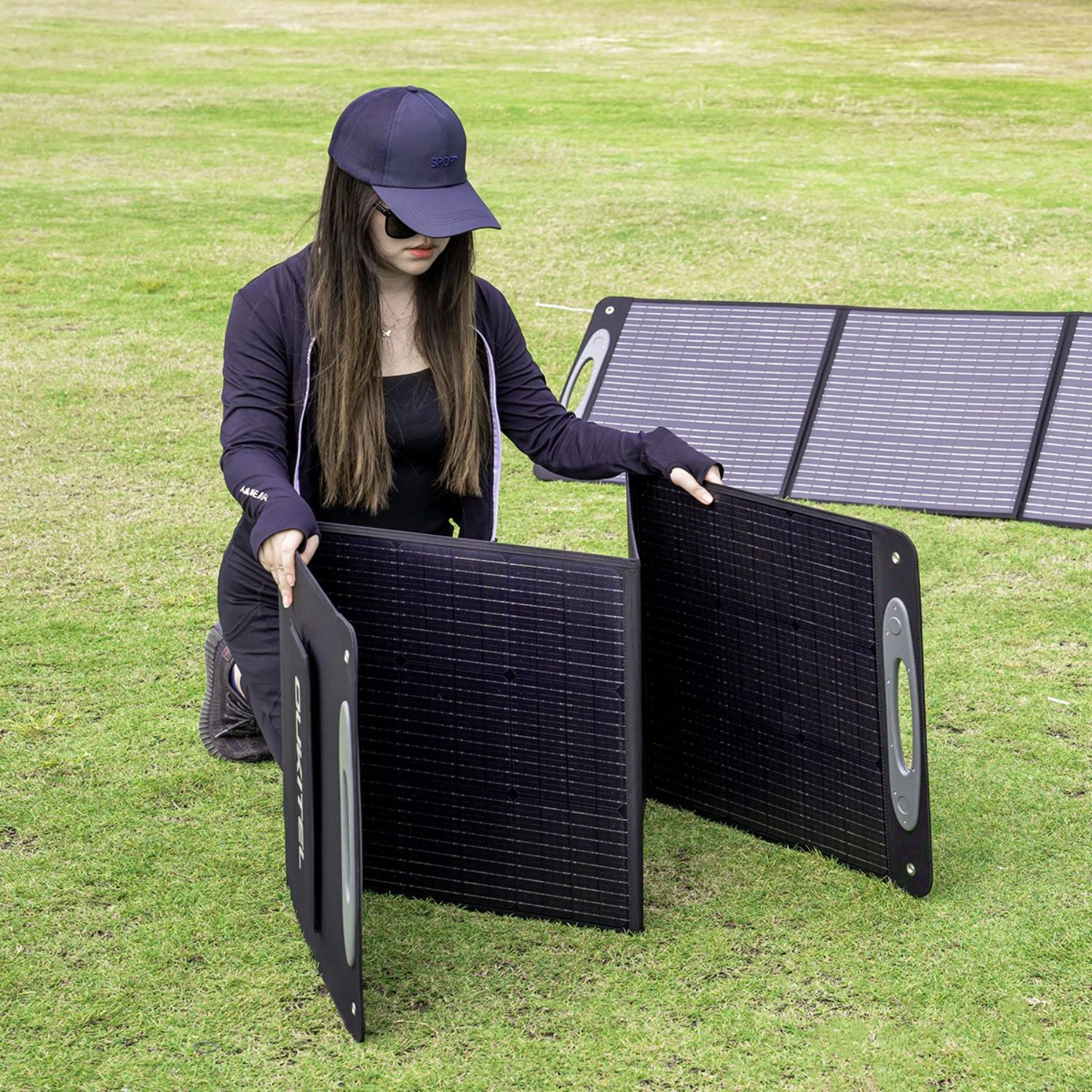 Person setting up a OUKITEL 200W Portable Solar Panel on grass