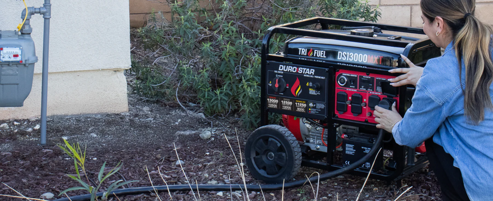 Person using a DuroStar DS13000MXT Tri-Fuel Generator outdoors