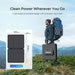 Person with a backpack holding a Renogy Solar Suitcase N-Type 100W Lightweight Portable Solar Panel with mountains in the background
