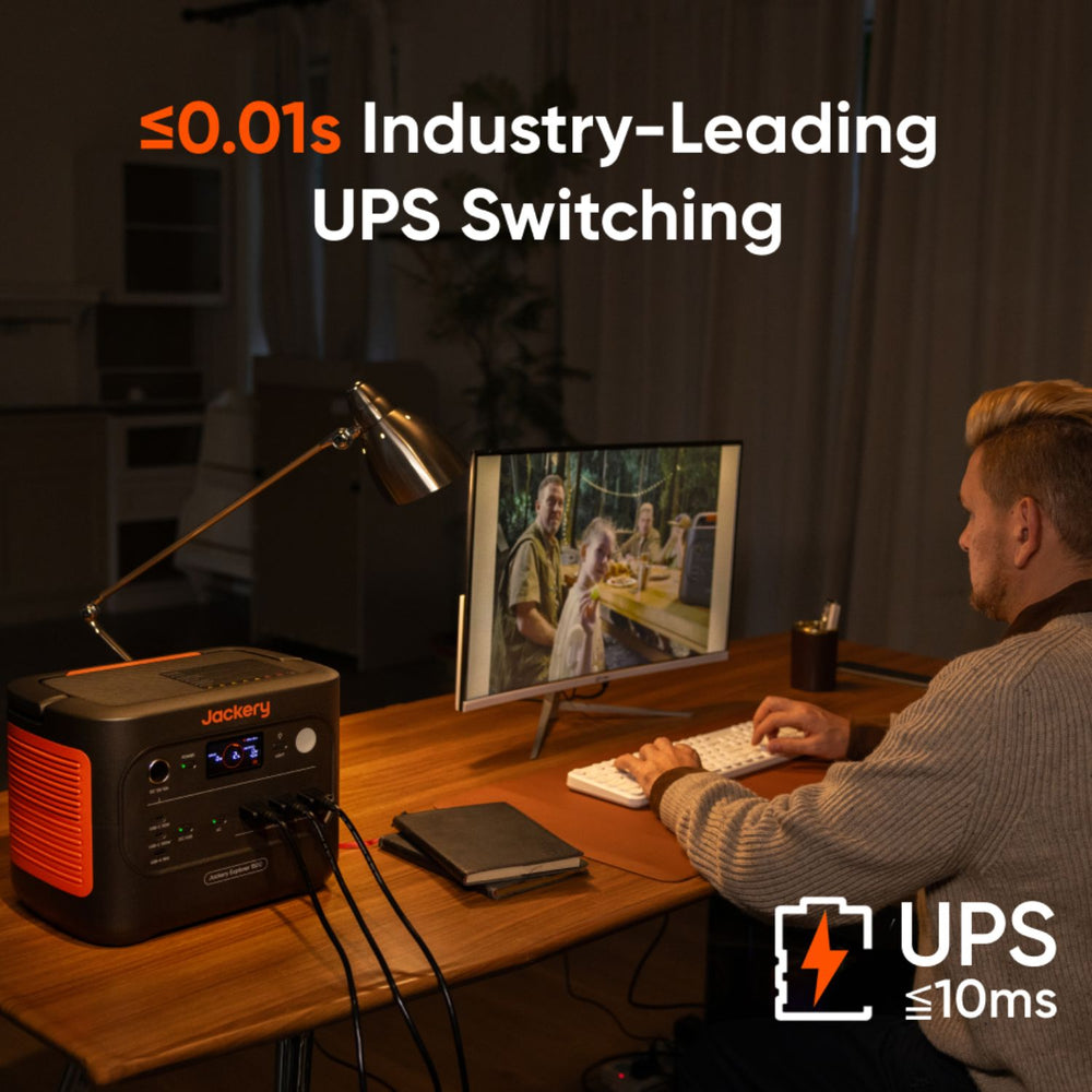 Person working at a desk with a Jackery Explorer 1500 v2 Portable Power Station emphasizing industry-leading UPS switching technology.