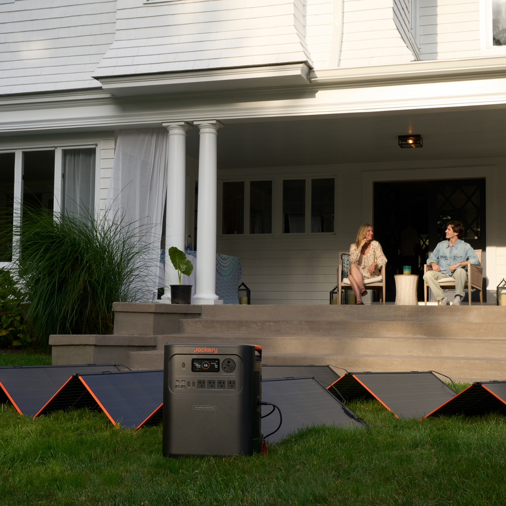 Portable power station on grass with people sitting on a deck in the background and Jackery HomePower 3600 Plus Portable Power Station 