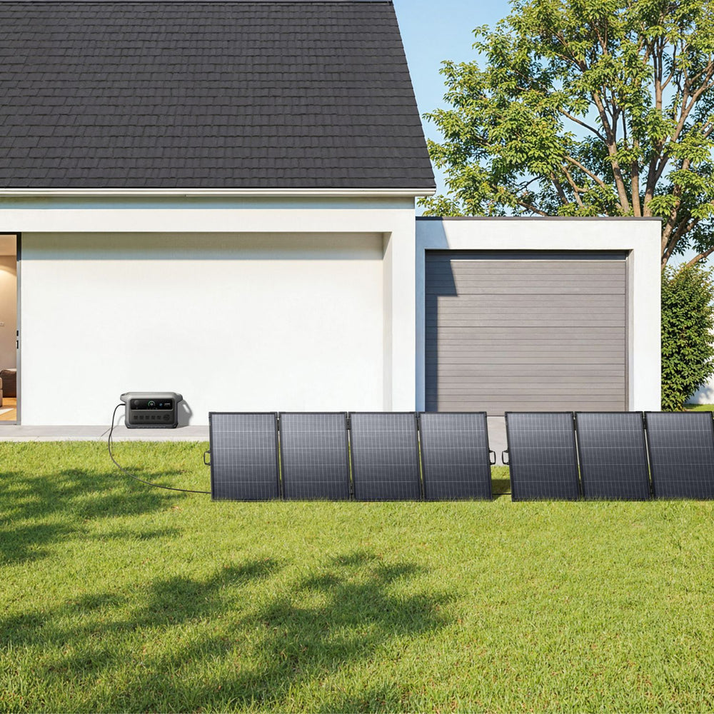 Solar panels on grass in front of a modern house connected to Anker SOLIX C2000 Gen 2 Portable Power Station