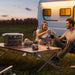 Two people sitting at a table outdoors with a camper van in the background with Anker SOLIX C2000 Gen 2 Portable Power Station in the table