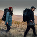Two people with backpacks walking through a desert landscape holding Jackery Explorer 600 v2