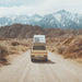Van with a camper shell on a desert road with mountains in the background with Go Power! Weekender ISW Solar Charging System