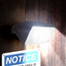 Wagan Tech 1000 Lumen Solar Wall Light On A Wall With Sign