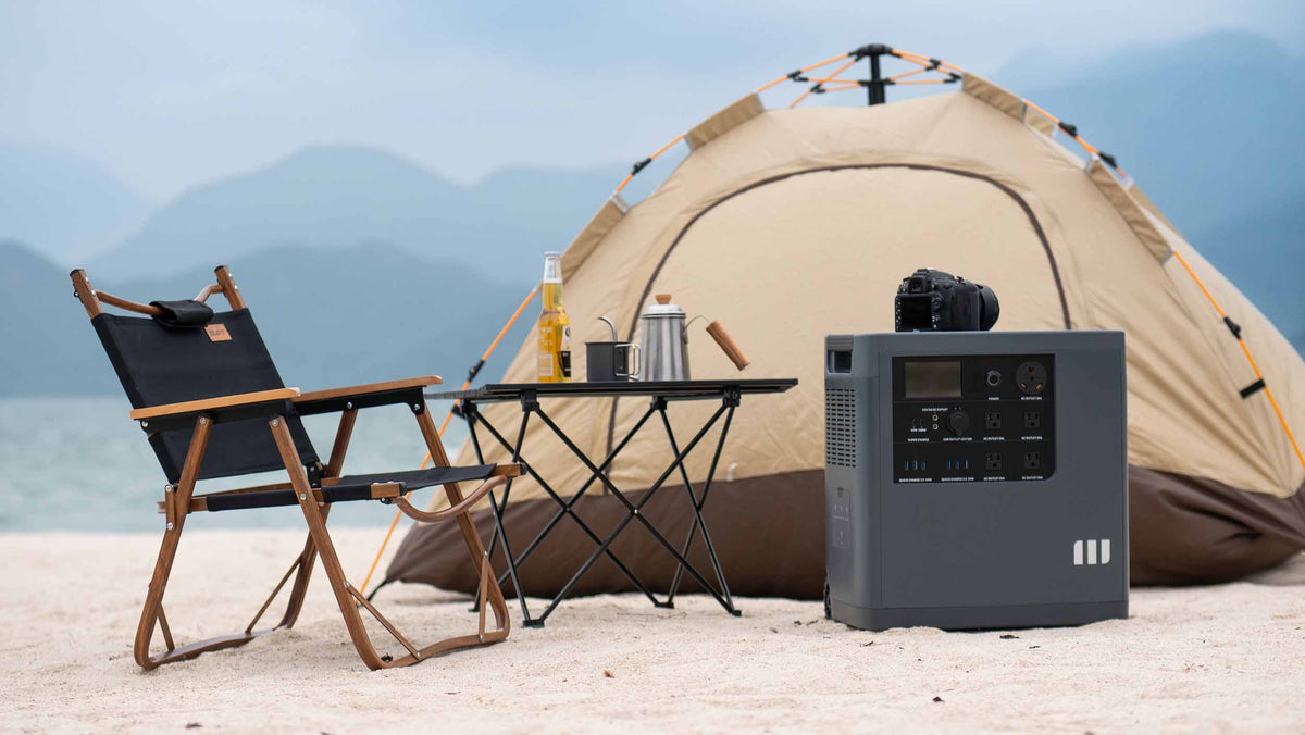 Mango Power E portable power station on the sand beside a tent, camp chair and table