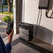Homeowner checking a phone app beside an EcoFlow TITAN battery stack in an open garage