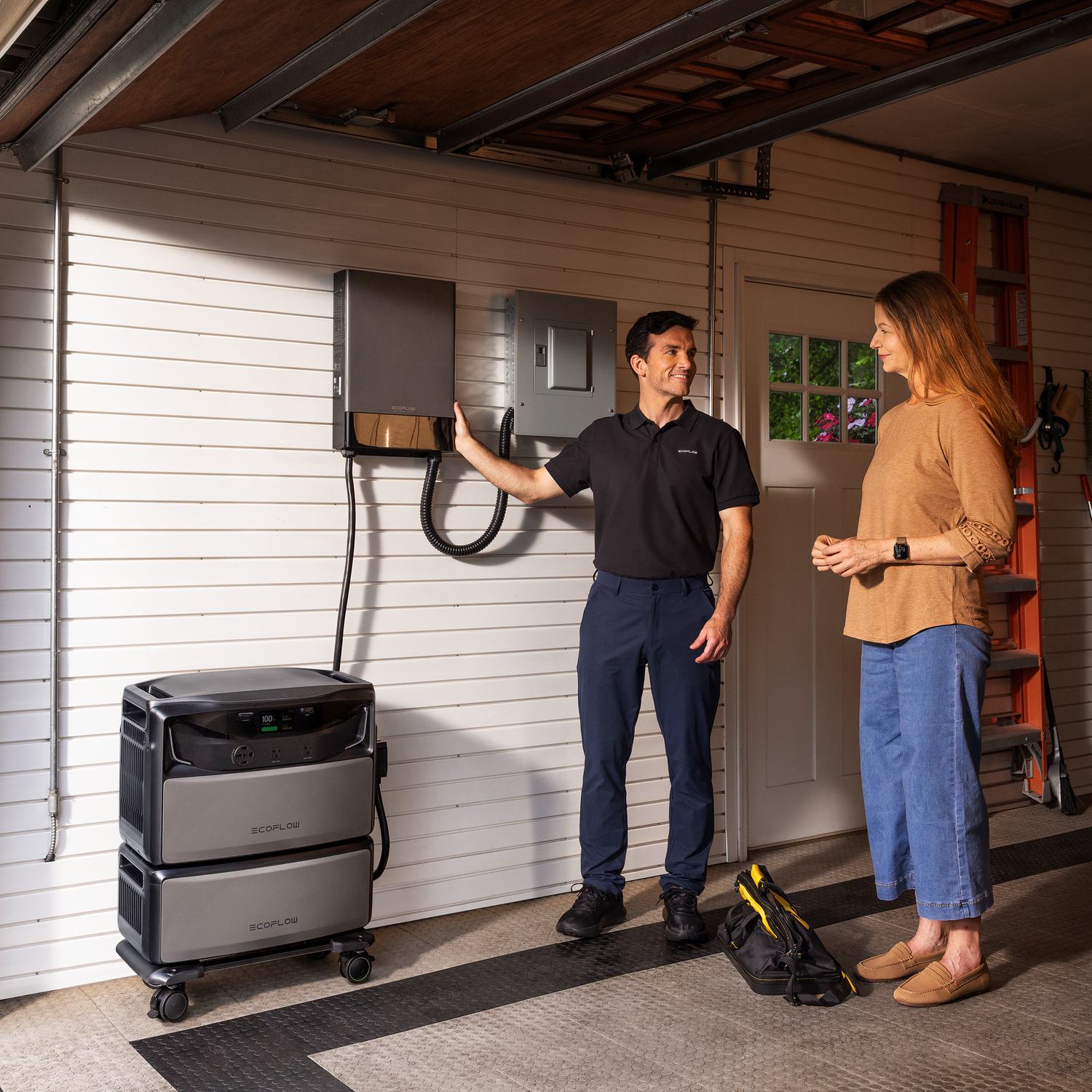 Installer showing a homeowner a wall-mounted Smart Home Panel 10 beside an EcoFlow TITAN 5000 Plus stack in the garage