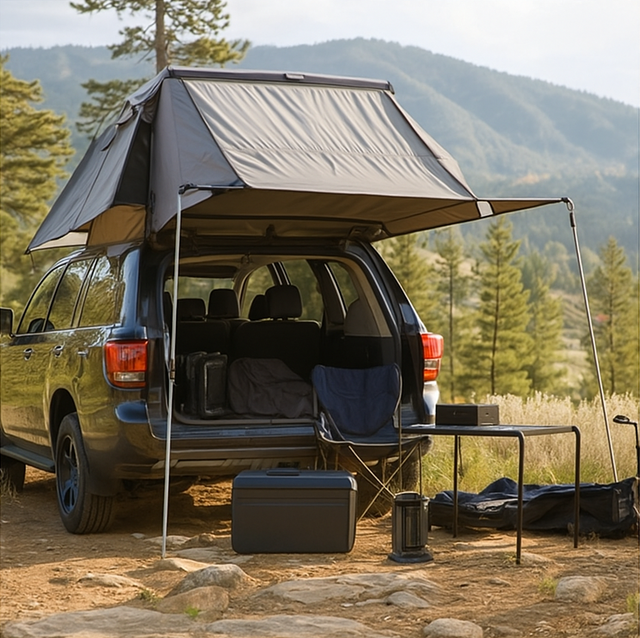SUV with a rear tent awning and camping gear at a mountain campsite