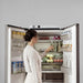Woman reaching into a refrigerator with a Jackery FridgeGuard on top of the fridge